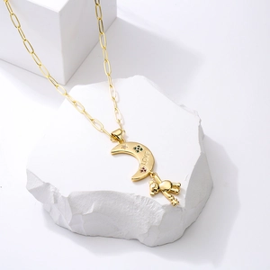 Golden crescent moon and bear pendant necklace with colorful stones on white stone