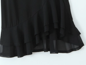 Detail of multi-layer ruffled hem with sheer mesh patchwork on a black sexy dress