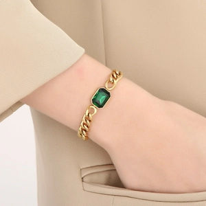 Gros plan d'un bracelet gourmette doré orné d'un grand cristal rectangulaire vert émeraude