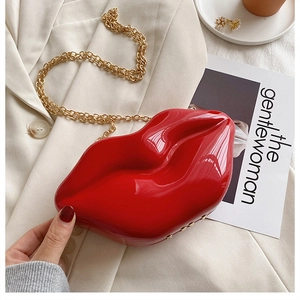 Macro detail of glossy red lip-shaped clutch bag with detachable gold chain strap