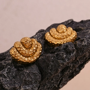 Macro shot of 18K gold plated fan-shaped earrings with hammered texture on black rock