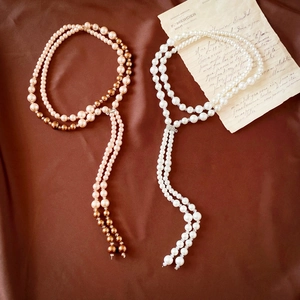 Elegant long pearl tassel necklace in white and champagne gold over brown silk