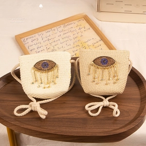Close-up of handwoven straw bags with beaded evil eye charms and tassel details