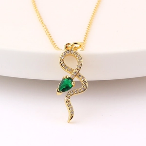 Détail macro du pendentif serpent doré avec pierre verte en goutte et cristaux