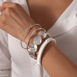 Close-up of four silver irregular geometric metal bracelets on a female wrist