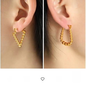 Detail of beaded gold V-shape and oval hoop earrings in polished geometric metal