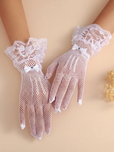 Detail of white lace bridal gloves featuring satin bows and rhinestone embellishments