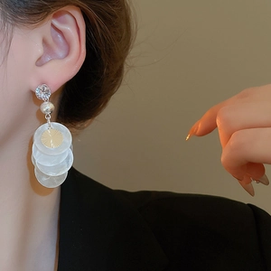 Detailed view of long tassel earrings with shell texture and sparkling zircon