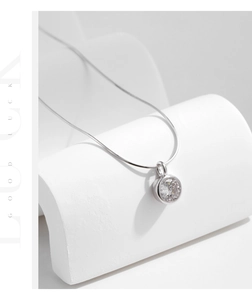 Macro detail of a brilliant round-cut solitaire pendant necklace with a sleek snake chain