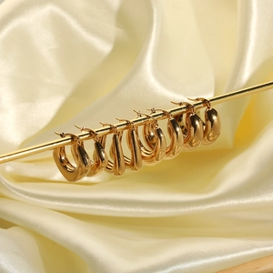 Fashionable 18k gold-plated C-shaped stainless steel earrings on beige silk background