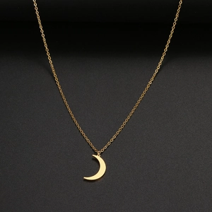 Gros plan d'un pendentif lune doré minimaliste avec une finition polie et une chaîne fine