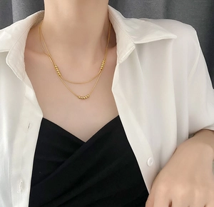 Detail of 18K gold double-layer titanium steel necklace with elegant round beads