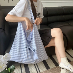 Side view of model wearing a large blue and white striped canvas tote with SUNY print