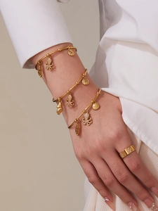 Detailed view of ocean-themed gold bangles with octopus and seashell charms on wrist
