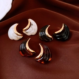 Close-up of 18K gold plated moon earrings in marble, black and amber resin finishes