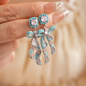 Détail macro de boucles d'oreilles nœud vintage avec cristaux roses et perles turquoise