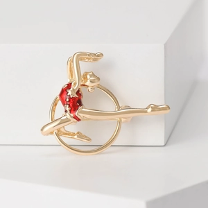 Detailed close-up of a golden gymnast brooch with red enamel coating and white dots