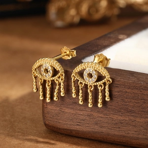 Macro view of gold S925 sterling silver evil eye earrings with diamond inlay and tassel