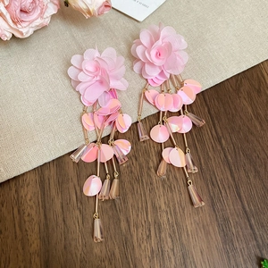Detailed shot of pink fabric flower earrings with sparkling sequins and bead tassels