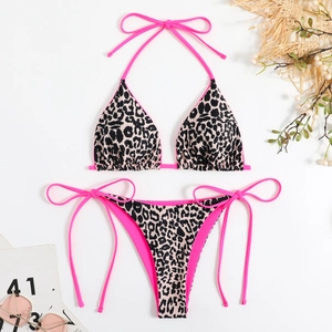 Flat lay of leopard print bikini with neon pink straps and beach accessories decoration