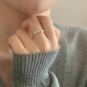 Close-up of minimalist 925 silver beaded open ring worn on a finger with knitwear