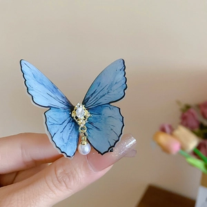 Détail de la pince à cheveux papillon bleu avec strass et perle factice suspendue