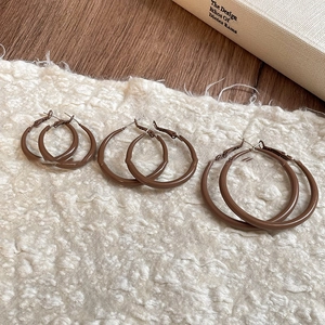 Three pairs of retro brown resin hoop earrings in different sizes on minimalist background