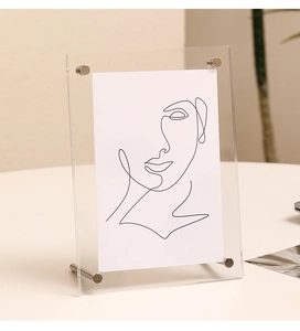 Detail of transparent acrylic photo frame with silver metal support bolts on desktop