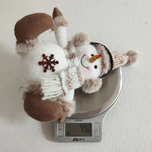 Knitted snowman plush toy Christmas ornament weighing 490g on a digital kitchen scale