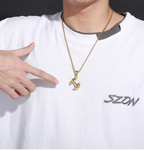 Close-up of golden dumbbell pendant necklace worn by model on a white t-shirt