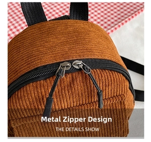 Detail of brown corduroy backpack with dual resin zippers and black woven pullers