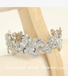 Detailed macro shot of silver camellia flower charms on a stainless steel cuff bracelet