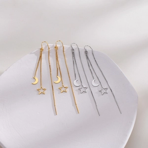 Detailed view of gold and silver long tassel star and moon earrings on white tray