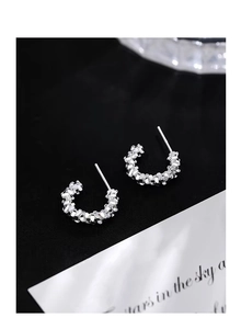Macro shot of S999 sterling silver C-shaped earrings with irregular crushed silver texture