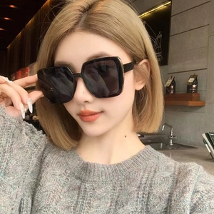 Detailed close-up of a model wearing black round semi-rimless oversized fashion sunglasses