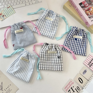 Sachets de rangement en tissu à cordon avec motifs floraux et rayures sur bureau blanc