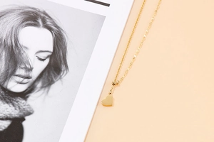 Detail shot of a polished golden heart pendant necklace on a lifestyle background