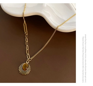Close-up of golden sun pendant with oval brown tiger eye stone on mixed link chain