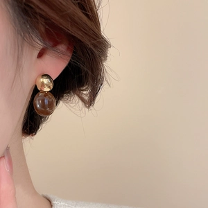 Détail de boucles d'oreilles en résine ambrée avec clous en métal doré et vintage