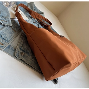 Detail view of large brown canvas tote bag with adjustable wide fabric shoulder strap
