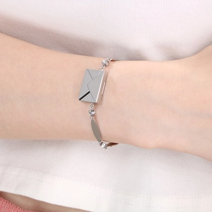 Detail of silver envelope pendant bracelet with rhinestones worn on a female wrist