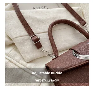 Détail de la boucle argentée ajustable et cuir marron à grain de litchi du sac