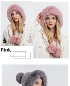 Close-up of pink faux fur winter hat featuring plush earflaps and decorative pom-poms