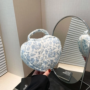 Detailed close-up of blue floral quilted heart makeup bag with secure zipper closure