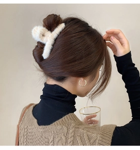 Détail d'une pince à cheveux en peluche crème portée pour un style hivernal doux