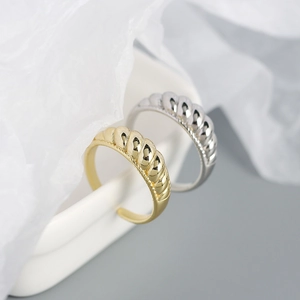 Detail of gold and silver croissant rings with a twisted texture on a white stand
