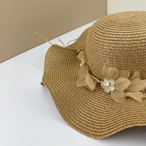 Détail du chapeau de paille d'été avec fleurs en dentelle et perles élégantes
