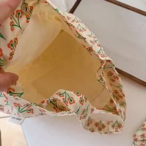 Detail of the cotton shoulder bag showing inner lining, open pocket, and brand tag