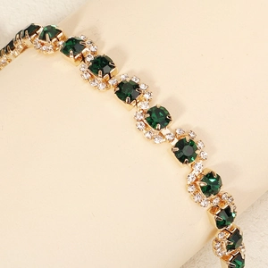 Close-up of golden bridal hair comb with green emerald-cut stones and clear crystals