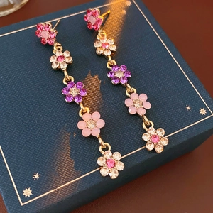 Detail of colorful crystal flower tassel earrings on a luxury navy blue jewelry box